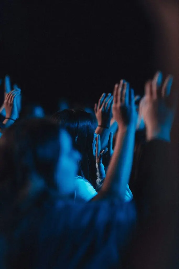 Vertical shot of believers in worship gathered in a hall with blue light effect