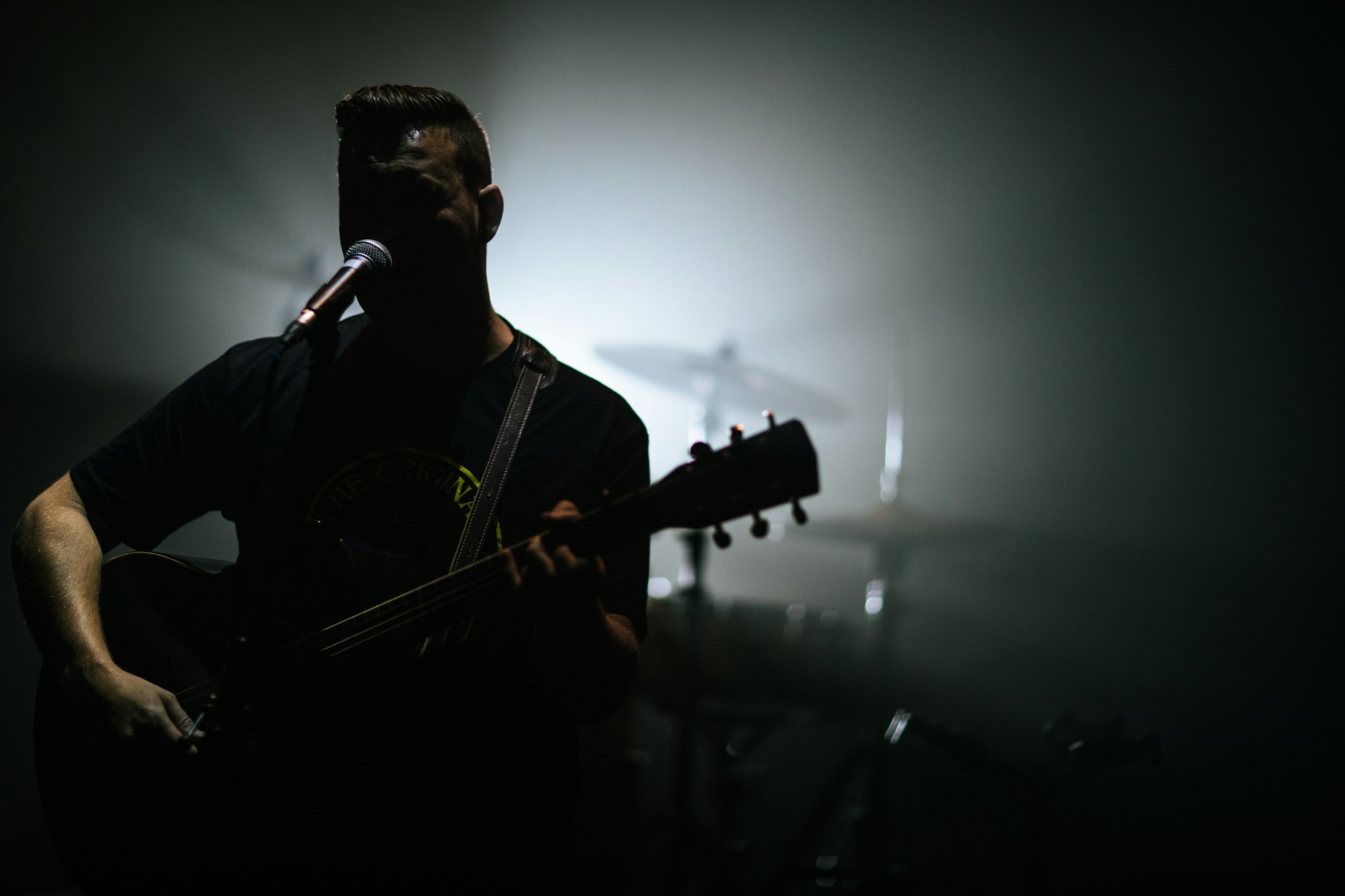Guy singing in a worship band at church with his guitar